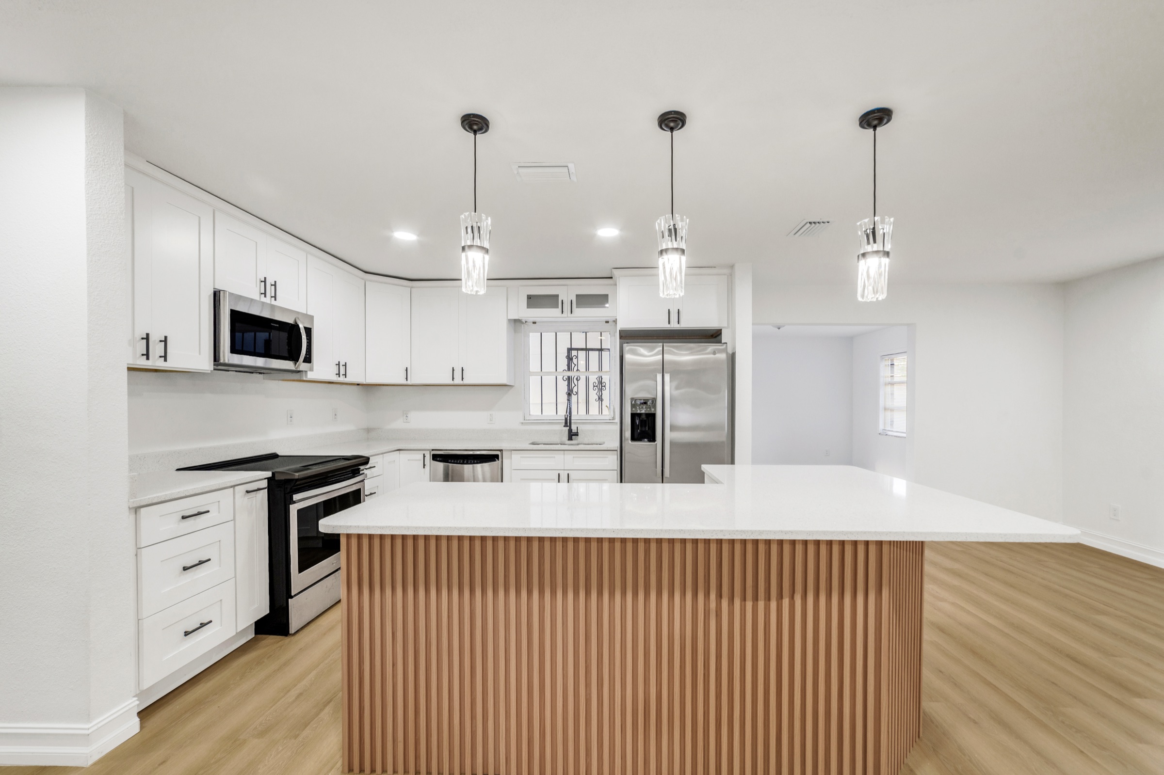 Listing photography Tampa FL — bright white kitchen with warm wood-wrapped island and pendant lights