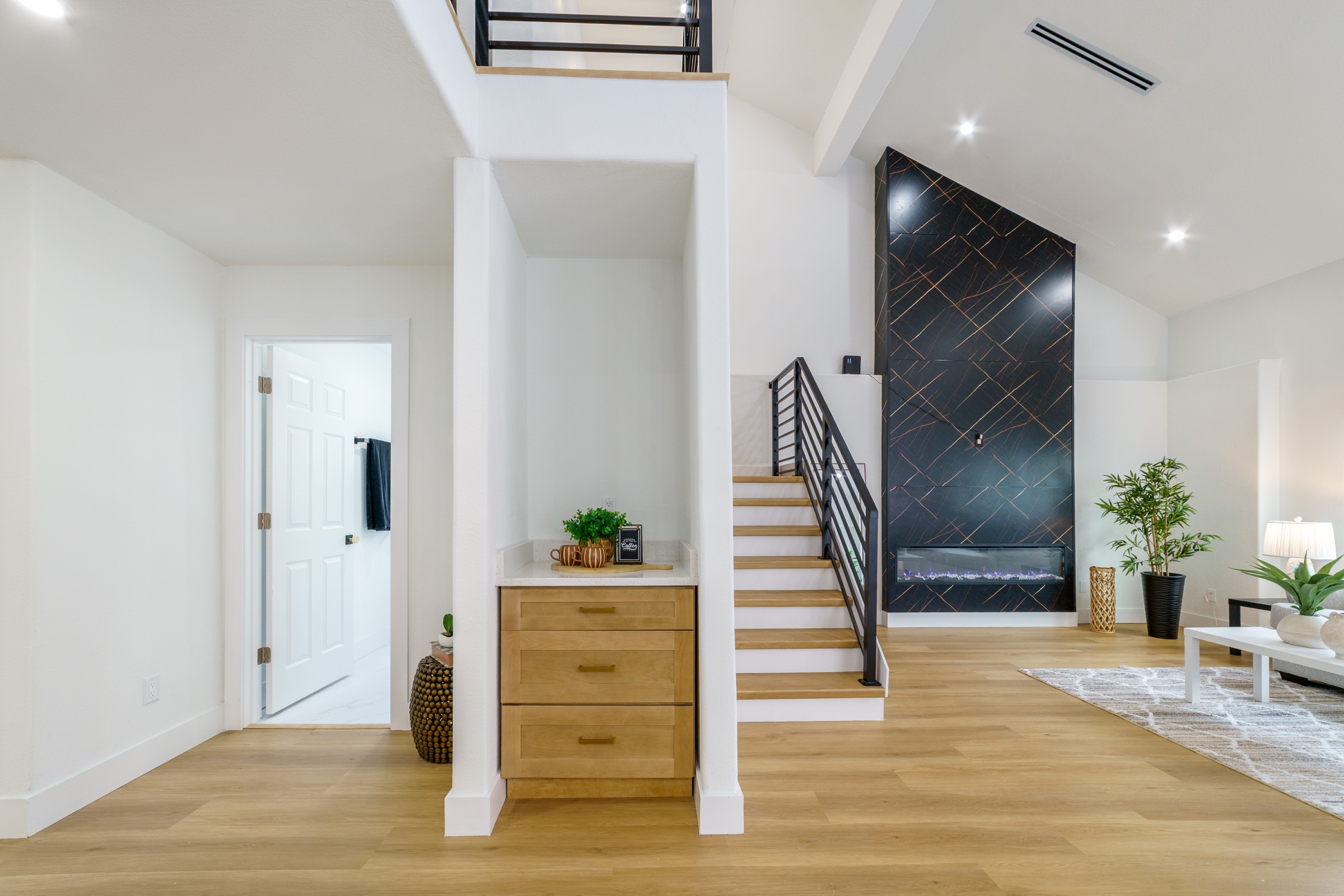 Real estate interior photography Tampa — modern staircase with black geometric fireplace feature wall