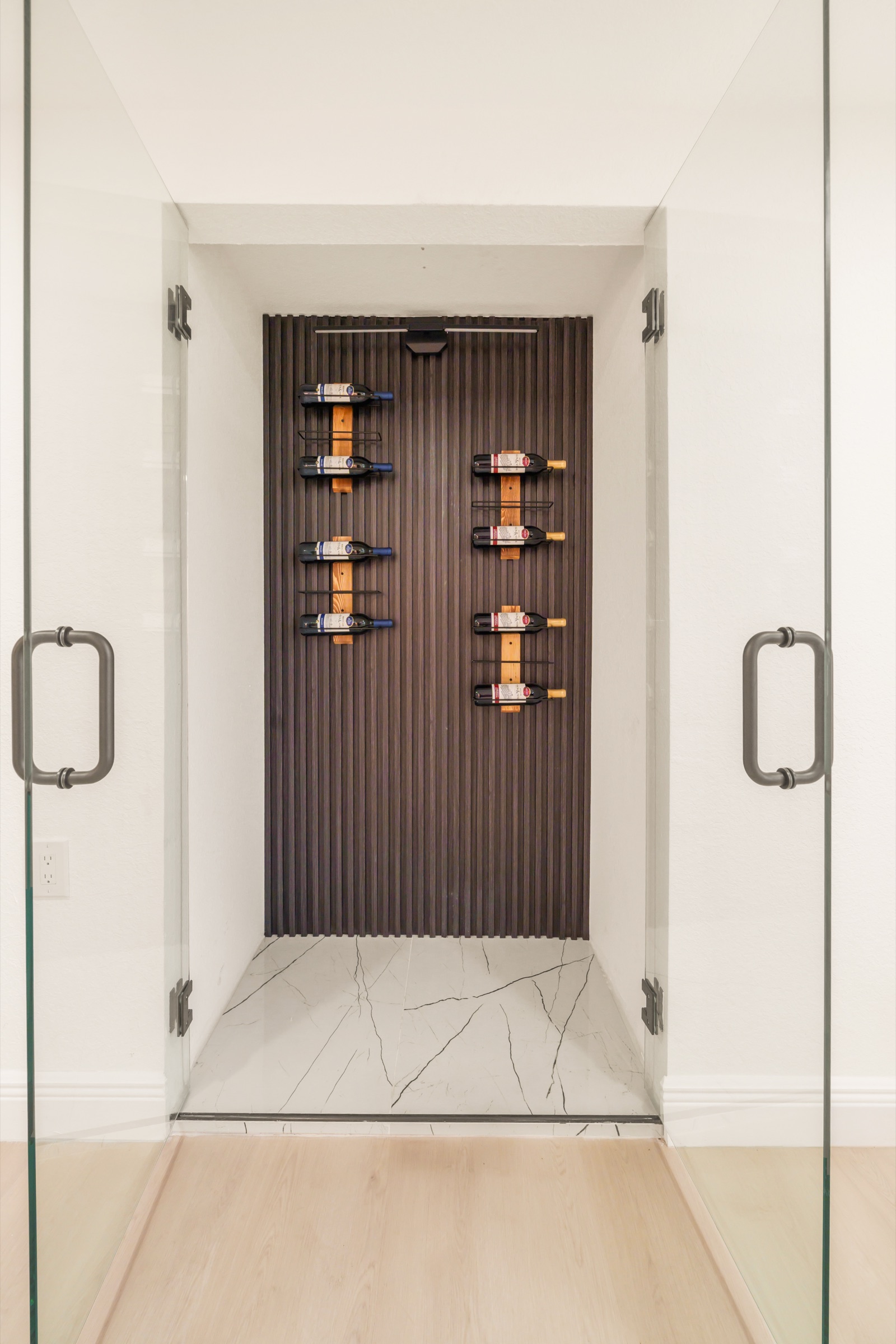 Luxury home photography Tampa — custom glass wine cellar with marble floor and curated collection